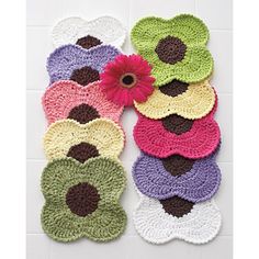 several crocheted flower coasters on a white tile floor with a pink flower in the center