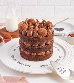 there is a chocolate cake on the plate with spoons next to it and milk in the background