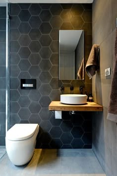 a modern bathroom with grey hexagonal tiles on the wall and wooden countertop