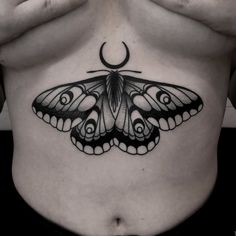 a woman's stomach with a butterfly tattoo on her belly and the moon behind it