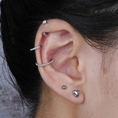 a close up of a person's ear with three piercings