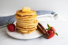 a stack of pancakes on a plate with cinnamon and strawberries next to the stack