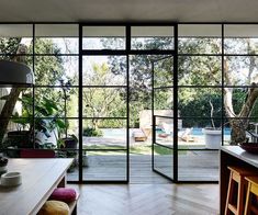 the inside of a house with large glass doors leading to an outdoor pool and deck area