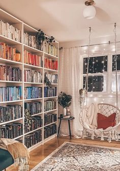 a living room filled with lots of furniture and bookshelves next to a window