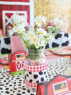 a mason jar filled with daisies on top of a black and white table cloth