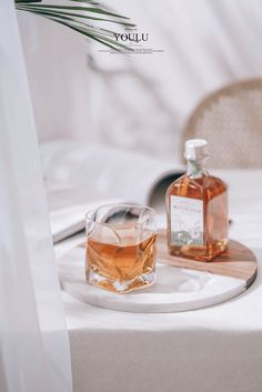 two bottles of alcohol sitting on top of a table next to a glass filled with liquid