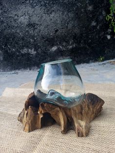 a glass vase sitting on top of a piece of wood