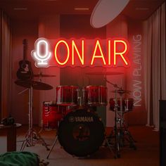 there is a neon sign that says on air next to drums and guitars in the room