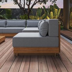 a couch sitting on top of a wooden floor next to a tree and bushes in the background