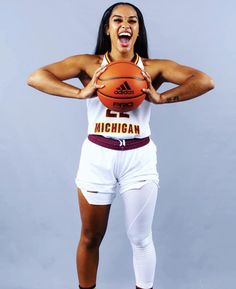 a woman holding a basketball in her right hand and making a funny face while posing for the camera