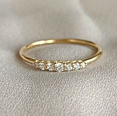 a yellow gold ring with five diamonds on the side, sitting on a white cloth