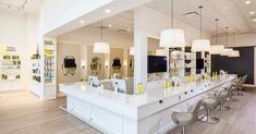 the interior of a salon with white counter tops and yellow lights hanging from the ceiling