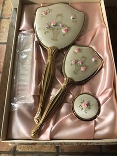 three spoons in a box with pink flowers on the side and gold trim around them