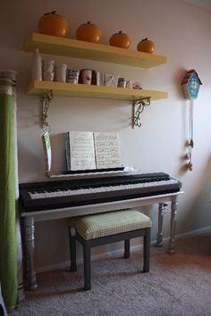 a piano sitting in the corner of a room next to a chair and shelf with books on it