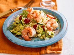 a blue plate topped with shrimp and veggies next to a glass of water