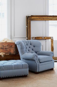 a blue and white striped chair sitting next to an old wooden box on the floor