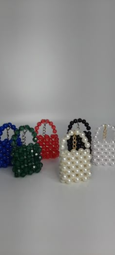 four beaded purses in different colors and sizes on a white surface with pearls