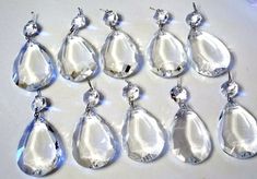 seven pairs of clear tear earrings on a white surface