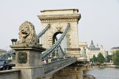 the bridge has lions on it and is next to a body of water with cars driving by