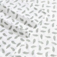 a white sheet with green leaves printed on the top and bottom part of it's sheets