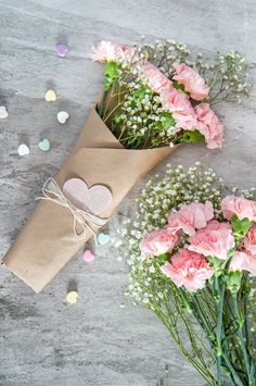 some pink flowers are in a brown paper bag and some white baby's breath