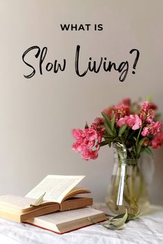 a vase filled with pink flowers next to an open book