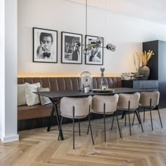 a dining room table with chairs and pictures on the wall above it in a modern style