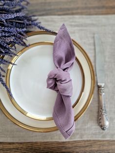 a place setting with silverware and lavender flowers on the tablecloth, along with napkins