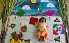 a young child laying on top of a blanket covered in paper flowers and kites