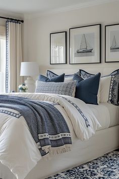 a bed with blue and white pillows in a bedroom next to two pictures on the wall