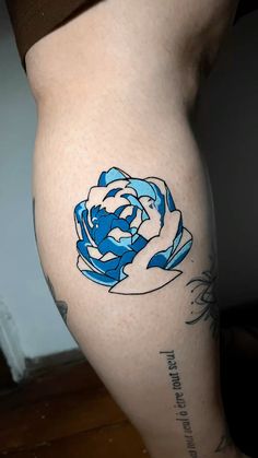 a woman's leg with a blue and white rose tattoo on the side of her thigh