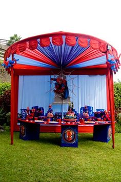 a red and blue tent set up for a party with decorations on the grass in front of it