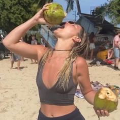 a woman drinking from a coconut on the beach