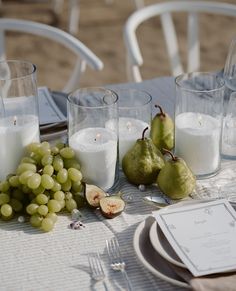 a table topped with glasses filled with white wine and fruit on top of a table