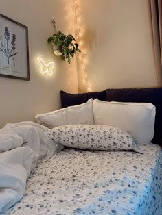 a bed with white sheets and blue flowers on it, next to a potted plant