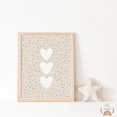 a small white star next to a wooden frame with two hearts on it, and a beige polka dot background