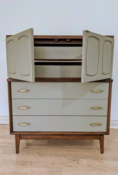 an old dresser with two doors open on the top and bottom drawers, in front of a white wall