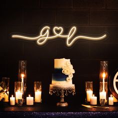 a wedding cake with candles on the side and lights in the air above it that spell out love