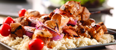 a plate with rice and chicken on it, garnished with cherry tomatoes next to other food items