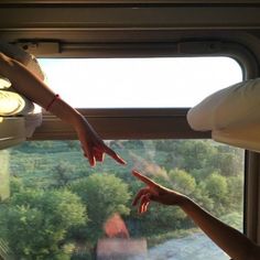 two people reaching out the window to touch each other's hand while on a train