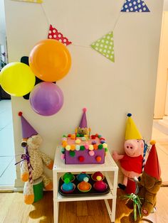 a birthday party with balloons and toys on the floor in front of a white wall