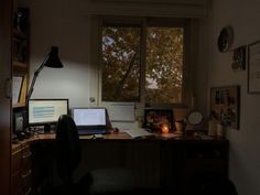 a desk with two laptops and a desktop computer on it in front of a window