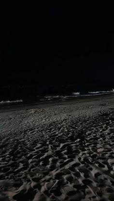 the beach is covered in dark sand at night, and there are no people on it