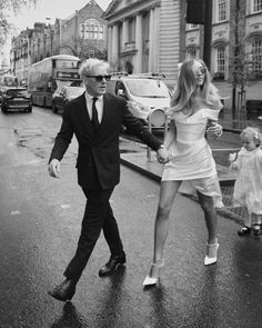 a man and woman crossing the street in the rain