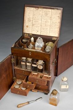 an old fashioned wooden box with drawers and other items in it on a white surface