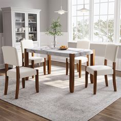 a dining room table with chairs and a rug on the floor