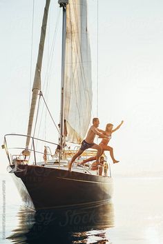 two people jumping off the side of a sailboat in the ocean by luma photography for stocks on artnetrave com