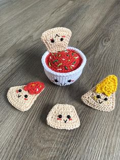 small crocheted food items sitting in a bowl on a wooden table next to each other