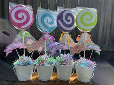 there are many candy decorations in buckets on the table