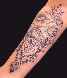 a black and white photo of a flower tattoo on the left arm, with an intricate design